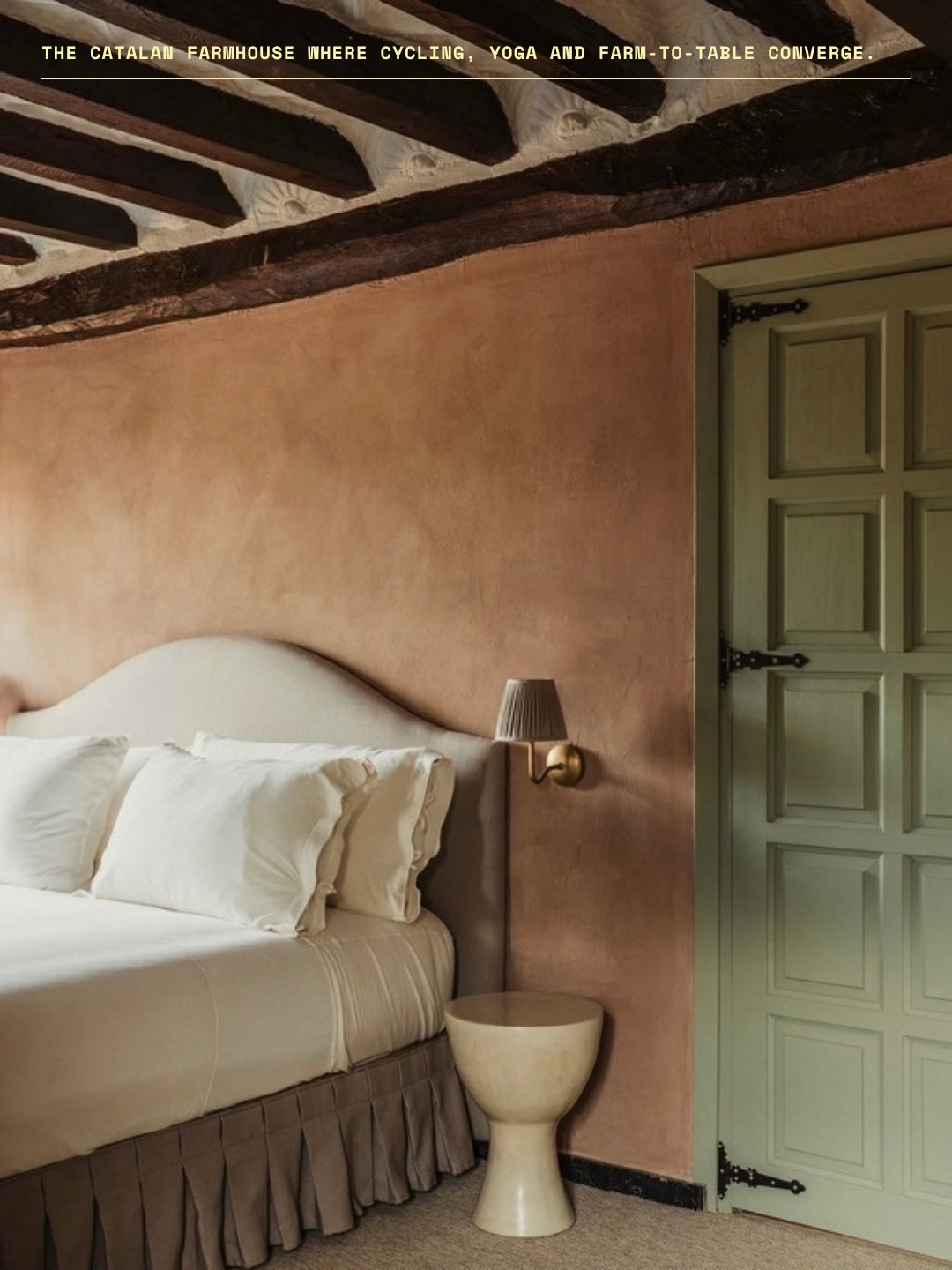 A bedroom with terracotta plaster walls, exposed beams and a sage green door