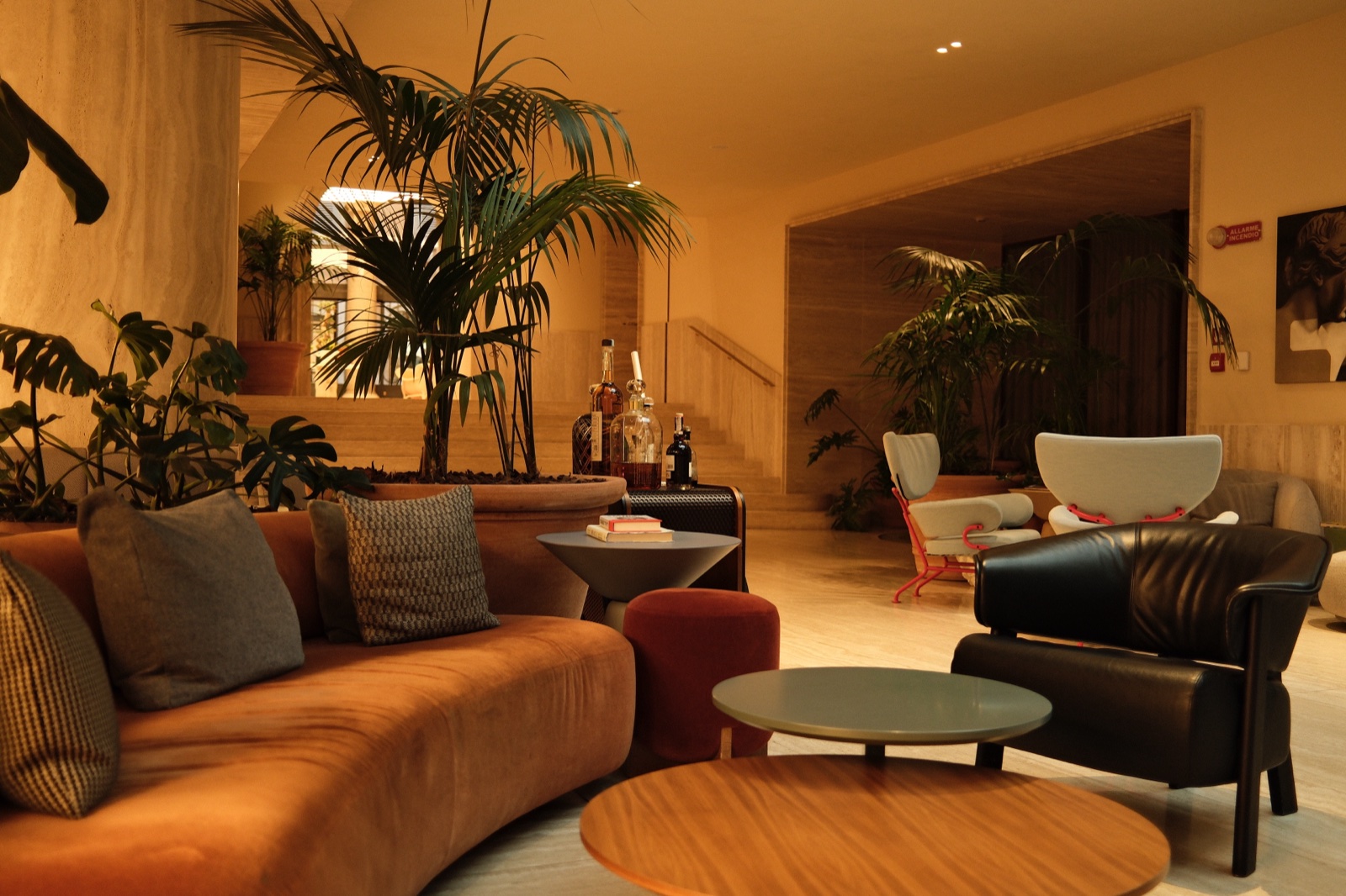 A warm travertine hotel lobby at golden hour with palms and designer seating